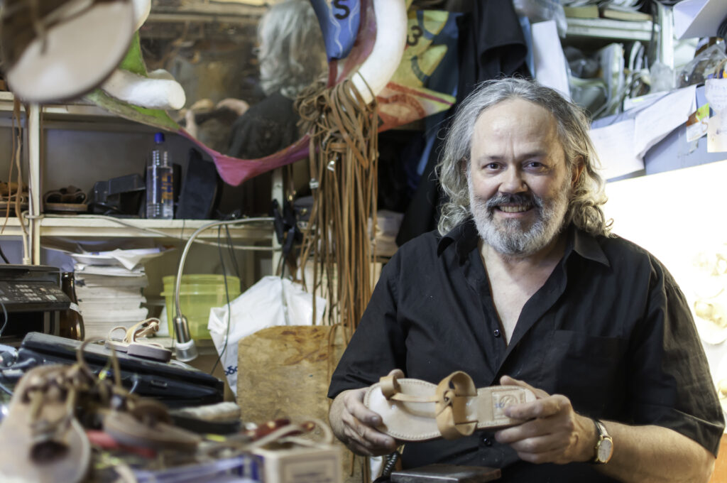 Melissinos Artisan inside his workshop, holding a sandal