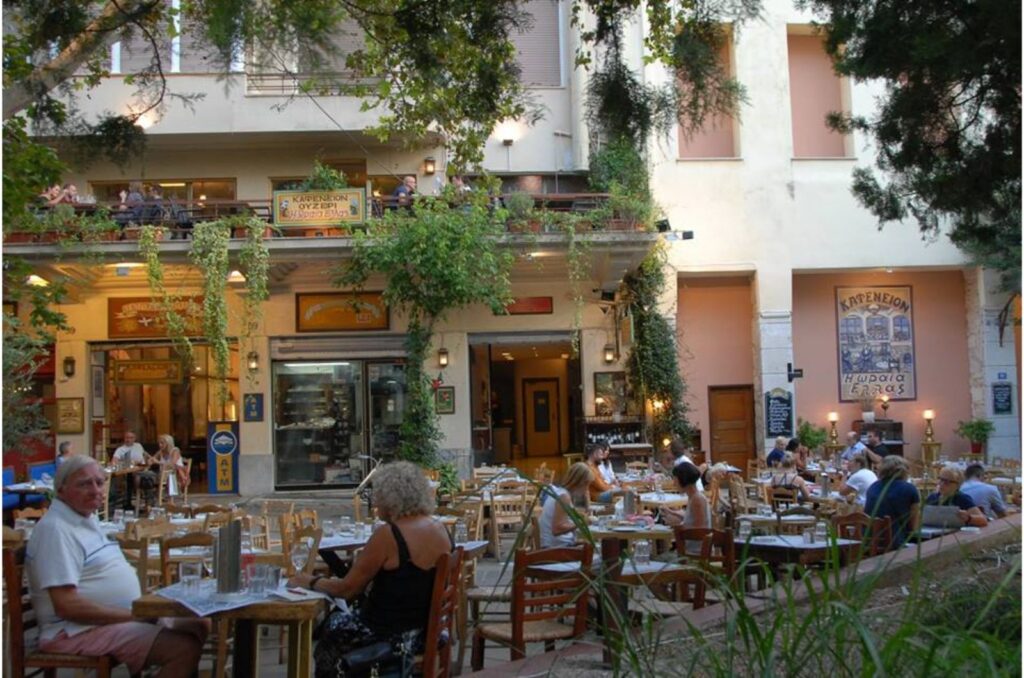 outdoor tables with some people sitting in the cafe Oraia Hellas